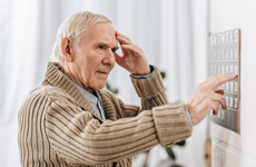 [Translate to French:] Old man touching his forehead standing infront of an button panel